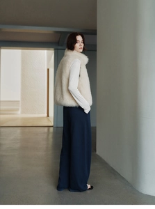 Chic cream faux fox fur vest paired with blue wide-leg trousers for a stylish winter look