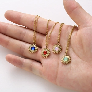 Golden sun pendant necklaces with colorful crystal centers in blue, red, pink, and green