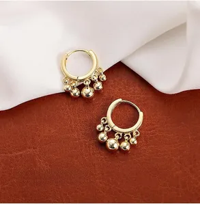 Detail of gold hoop earrings with alternating polished beads on leather background