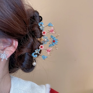 Détail du peigne à cheveux avec fleurs en émail et perle sur une chevelure brune