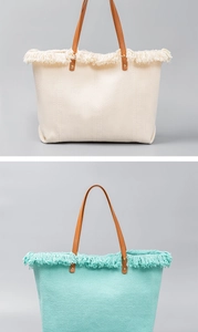 Close-up of woven canvas tote bags in cream and light blue with fringe and leather handles