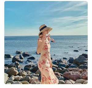 Outdoor shot of a wide-brim straw hat with black ribbon and floral beach dress