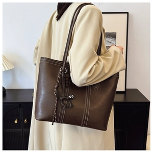 Detail of dark brown leather tote with contrast white stitching and cute cat charm