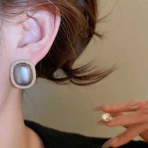 Detail of oval gold-plated earring with soft purple gemstone and zircon halo