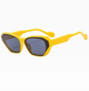 Detail view of stylish beige cat-eye sunglasses with yellow frames and dark grey lenses