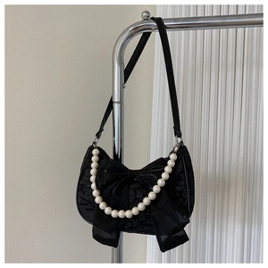 Detailed view of black lace handbag featuring a large silk bow and pearl bead handle