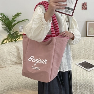 Detailed view of striped plush straps and spacious lotus root pink tote bag worn by model