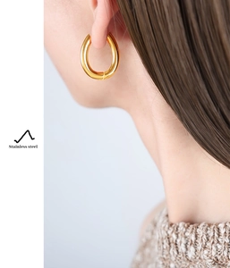 Macro detail of U-shaped gold plated stainless steel earring worn by a female model