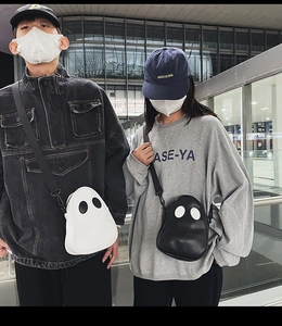 Close-up of black and white ghost shaped crossbody bags with cute eye details and zipper