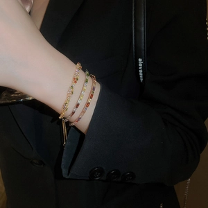 Close-up of three colorful rhinestone bracelets layered on wrist against dark background