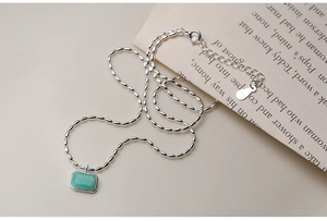 Close-up of S925 sterling silver chain with green rectangular stone on elegant paper