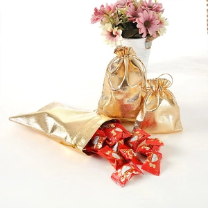 Detail of glossy gold drawstring jewelry gift bags with metallic texture and flowers