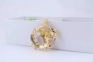 Close-up of golden dragon keychain with intricate metal textures and a small pearl accent