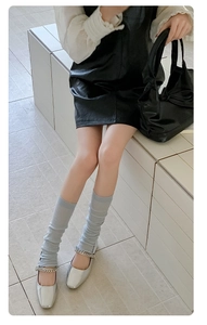 Close-up of light grey ribbed leg warmers paired with silver Mary Jane shoes