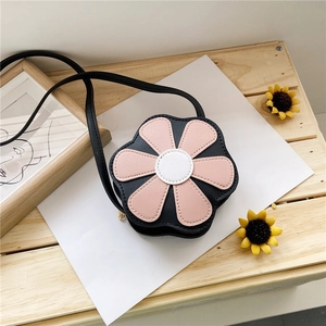 Close-up of black flower-shaped kids purse with pink petals and white core on wooden crate