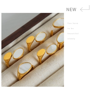 Macro view of gold plated oval signet rings with white mother of pearl inlay in a jewelry box