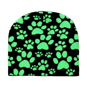 Detail shot of black knit beanie featuring neon green paw print jacquard patterns