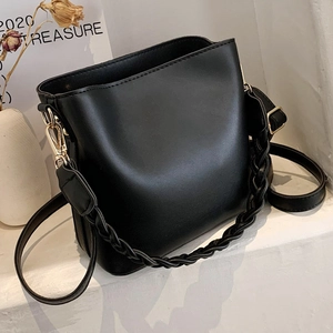 Modern black leather bucket bag with woven handle and gold hardware on white background
