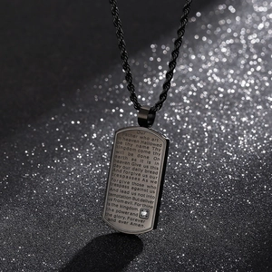 Vue macro du collier plaque militaire en acier noir avec gravure de prière et petit cristal