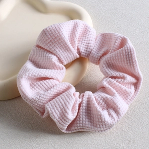 Detailed view of pink waffle texture fabric scrunchie on a decorative white tray