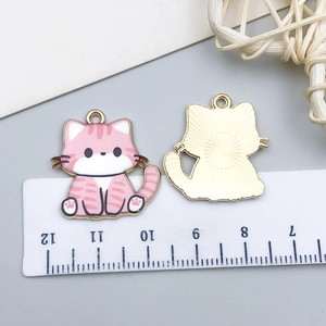 Front and back detail of pink enamel cat pendants showing 3cm size on a ruler scale
