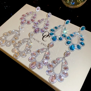 Close-up of sparkling water drop earrings in silver, pink, and blue in a jewelry box