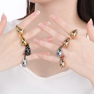 Detailed view of oversized teardrop rings in gold and silver with colorful rhinestones