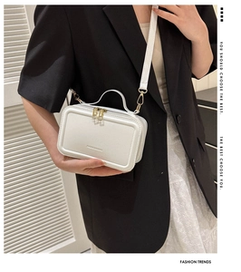 Detail view of white box-shaped handbag with Fashion Bag logo and golden hardware