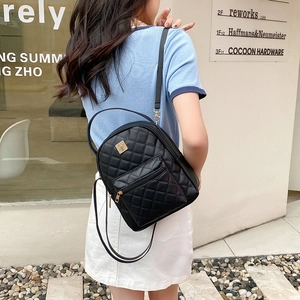 Chic black quilted leather mini backpack with gold hardware worn by a model in the city