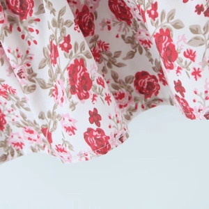 Nahaufnahme der Textur des floralen Stoffes mit roten Blumen und feinen Nähten