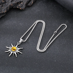 Detail of silver sun pendant with a yellow gemstone eye on a black stone background