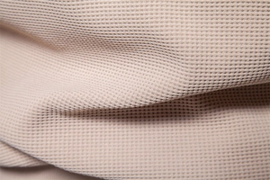 Detailed macro view of the apricot waffle knit fabric on a men's stand collar jacket