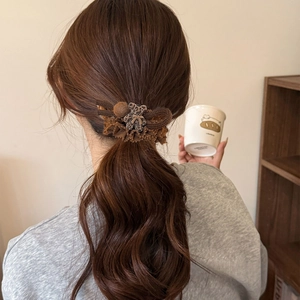Detail of leopard print bear hair tie on dark brown wavy hair with cozy aesthetic