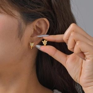 Detailed view of gold butterfly ear cuffs with sparkling clear stones on a model ear