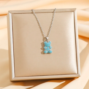 Collar de oso plateado con cristales azul claro sobre un joyero de color champán