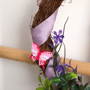 Pink felt butterfly and purple ribbon on decorative rattan Christmas wreath decor