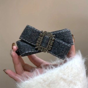 Détail d'un nœud papillon en laine grise avec coutures blanches et strass à la main