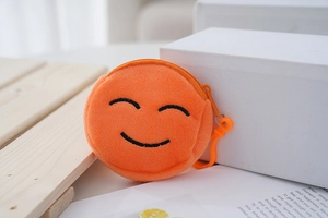 Detail of a mini orange plush coin purse with smiley face embroidery and plastic hook