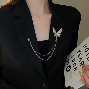 Detail of silver butterfly brooch with tassel chain and gray pearl on a black suit lapel