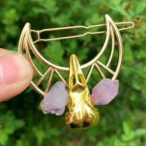 Close-up of gothic hair clip with crescent moon, raven skull and purple crystals