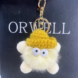 Detail of plush keychain with yellow knit hat, white faux fur and golden metal clasp