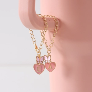 Close-up of pink butterfly and heart alphabet charms E and A on a gold cup chain