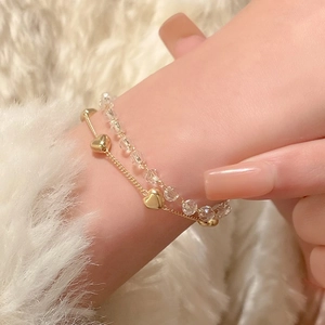 Pulsera de doble capa con corazones dorados y cuentas de cristal sobre piel blanca