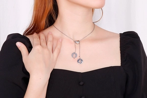 Gros plan sur collier en acier argenté avec fermoir coeur et pendentifs silhouettes