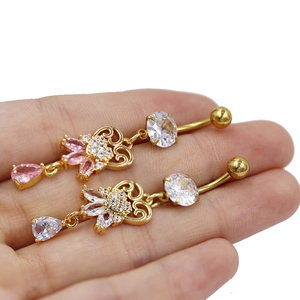 Detailed close-up of gold belly rings with marquise zircons held in a hand for scale