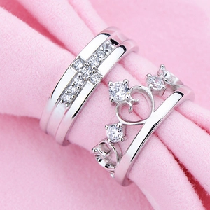 Silver crown and cross couple rings set with diamonds on soft pink velvet base
