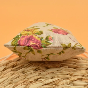 Close-up of a floral print cotton sachet bag on a woven mat with warm background