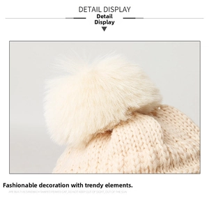 Détail de la maille épaisse et du pompon en fausse fourrure sur bonnet d'hiver beige