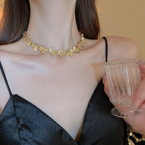 Close-up of a gold-plated clover necklace worn by a model with an elegant polished finish