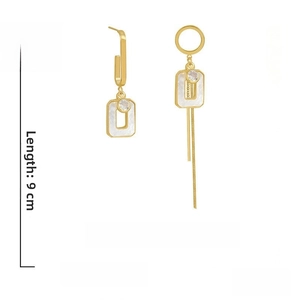 Detail of gold asymmetrical earrings with acrylic squares, rhinestones, and long tassels